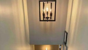 Een trap met een leuning, een lamp erboven en een deur aan de bovenkant.