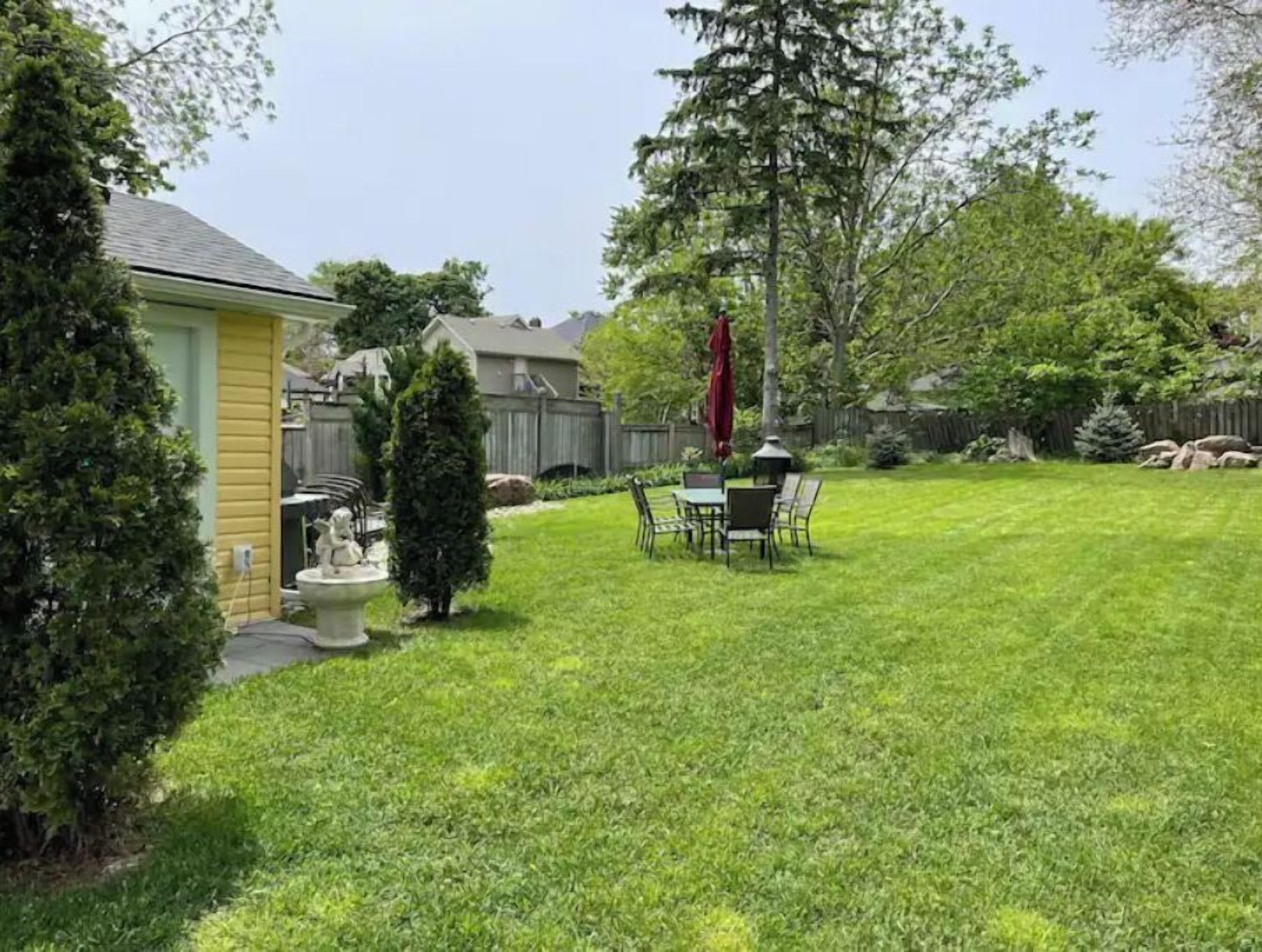 Un jardin avec une pelouse, une table de patio et des chaises.