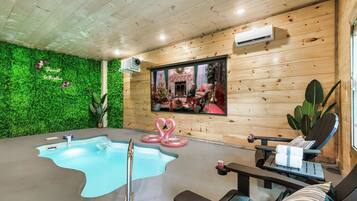 A modern indoor pool area with a wooden ceiling, green wall, and a large window.