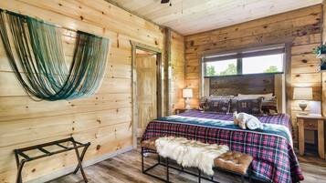 Une chambre dans une cabane en bois, avec un lit, un banc et un hamac.
