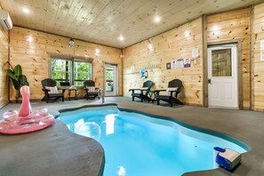 Une cabane en bois avec une piscine, des chaises et une porte.