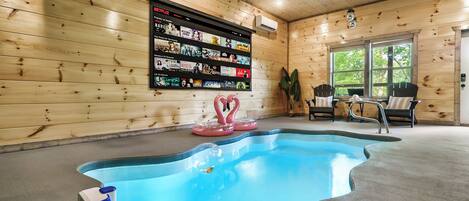 Un área de piscina con interior de madera, una pantalla de Netflix y sillones de descanso.