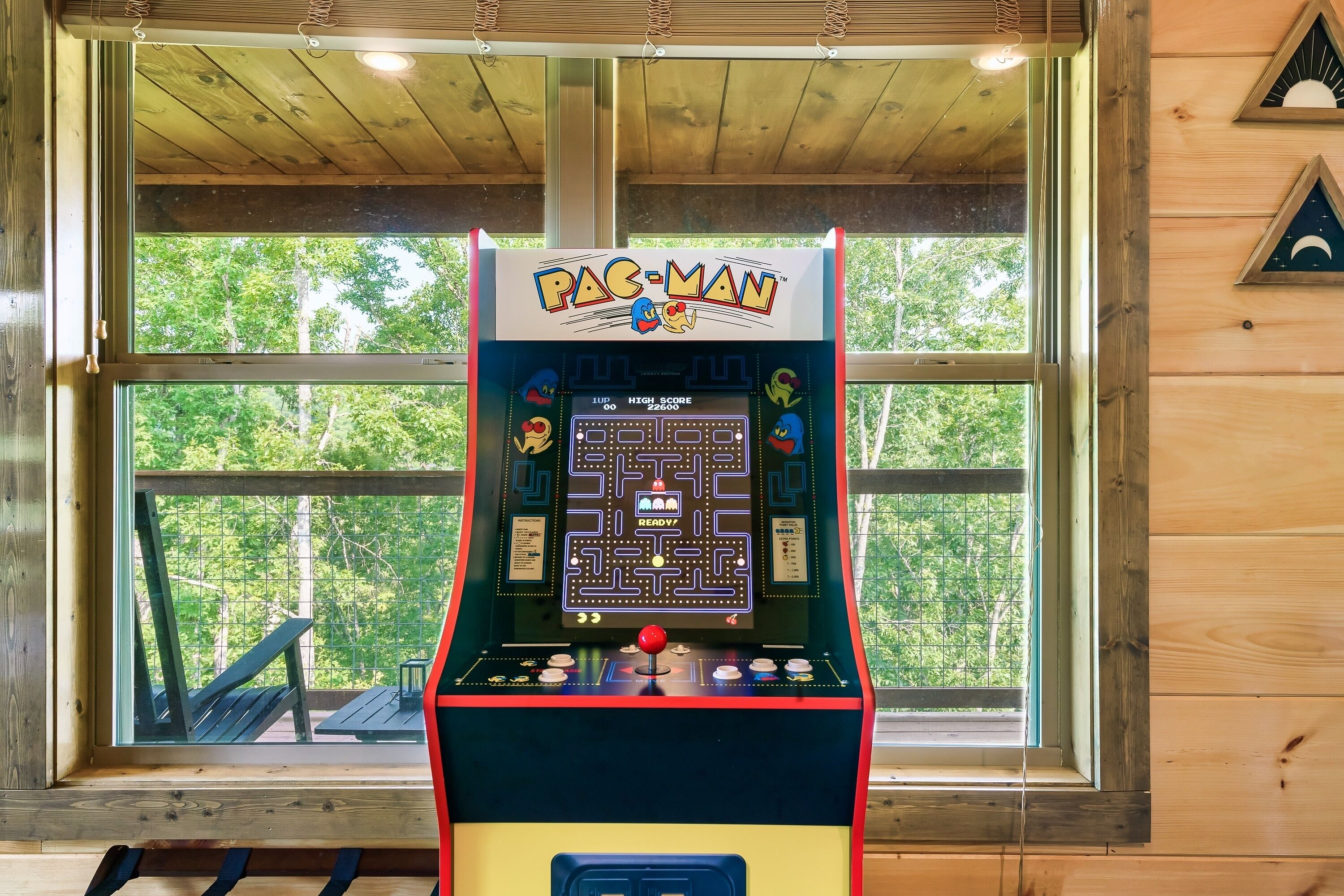 Una màquina recreativa de Pac-Man en una cabana de fusta amb un finestral gran.