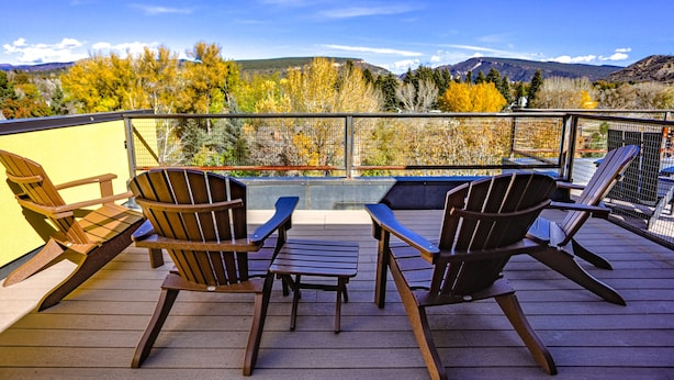 A deck with Adirondack chairs and a table, overlooking a mountainous landscape with autumn foliage. - Modern Townhouse on the River w/AC, Roof Top Deck (Durango)