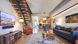 A modern living room with a staircase, a sofa, a coffee table, and a TV. - Modern Townhouse on the River w/AC, Roof Top Deck (Durango)