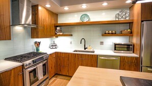 A modern kitchen with wooden cabinets, stainless steel appliances, and a white countertop. - Modern Townhouse on the River w/AC, Roof Top Deck (Durango)