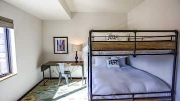 Un lit superposé avec un bureau et une chaise, une lampe et un tableau encadré au mur.