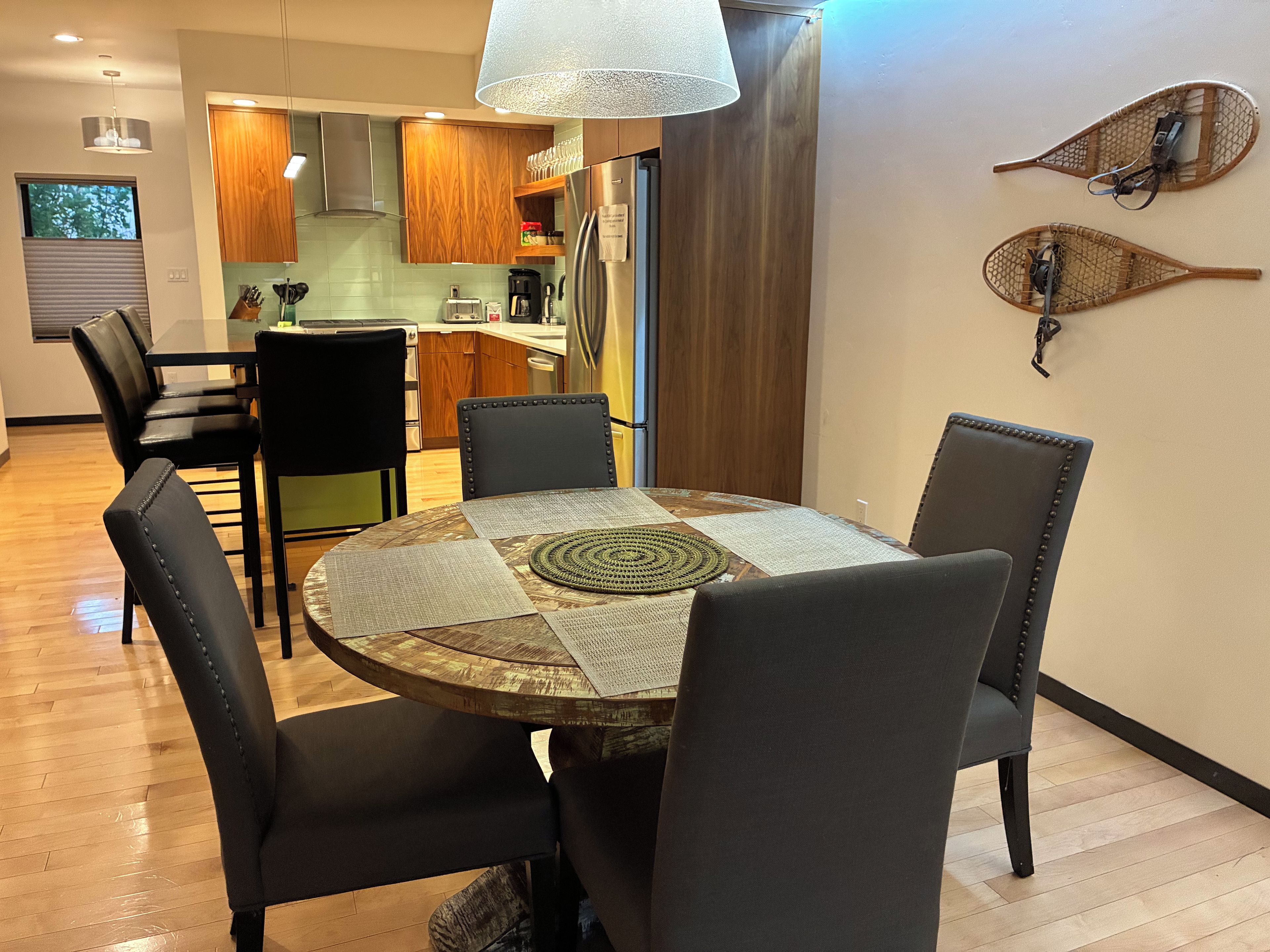 Un espace repas comprenant une table ronde, six chaises et un tapis décoratif placé au centre.