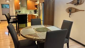 Un espace repas comprenant une table ronde, six chaises et un tapis décoratif placé au centre.