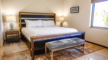 Une chambre à coucher avec un lit, des tables de chevet, un banc et une fenêtre.