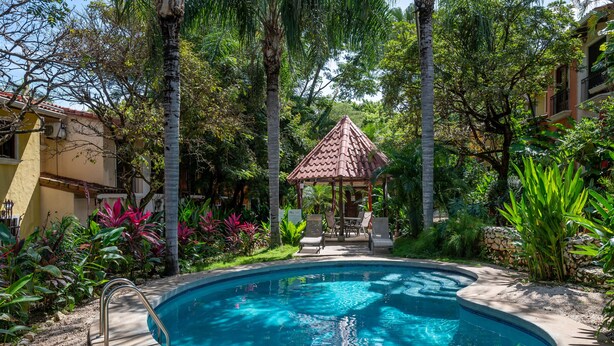 A swimming pool surrounded by lush greenery and a gazebo.