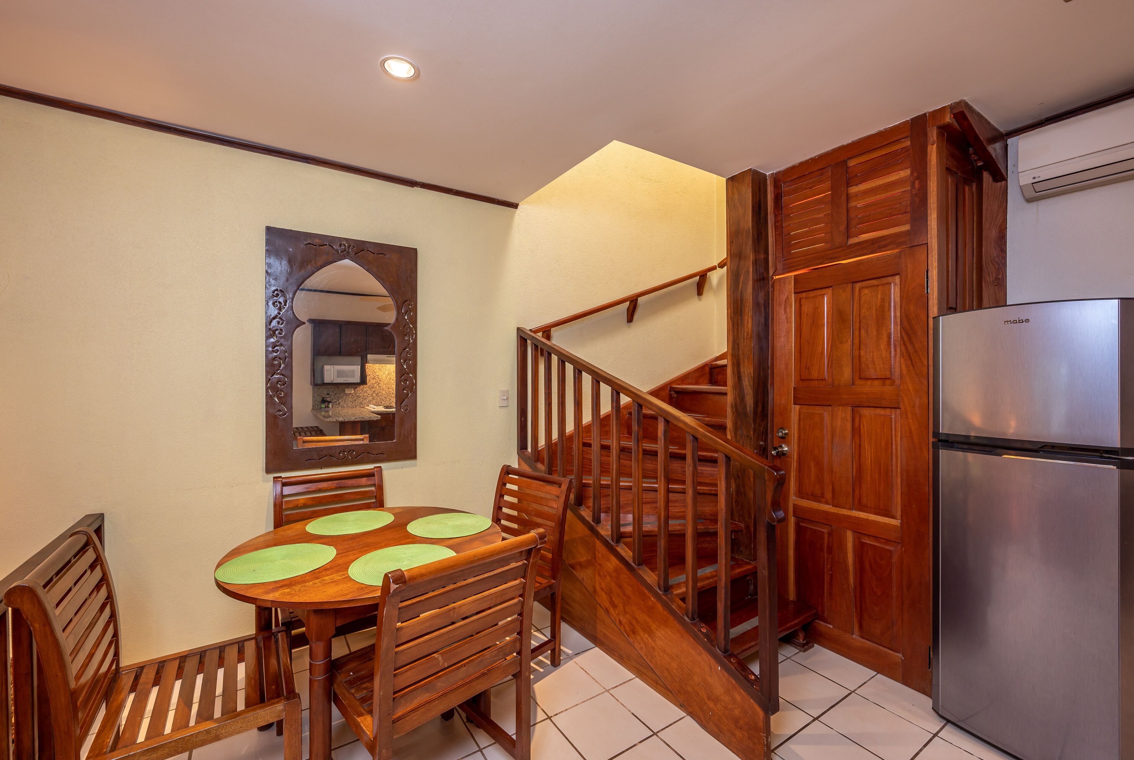 Un coin repas avec une table et des chaises en bois, un escalier en bois et un réfrigérateur en acier inoxydable.