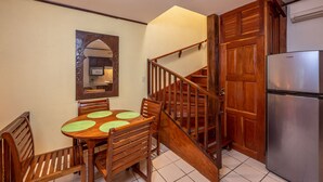 A dining area with a wooden table and chairs, a wooden staircase, and a stainless steel refrigerator.