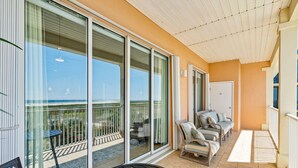 A balcony with a glass door, a table with a plant, and a seating area with chairs.