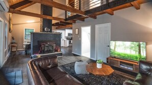Un salón amplio con chimenea, sofá de cuero y televisor.