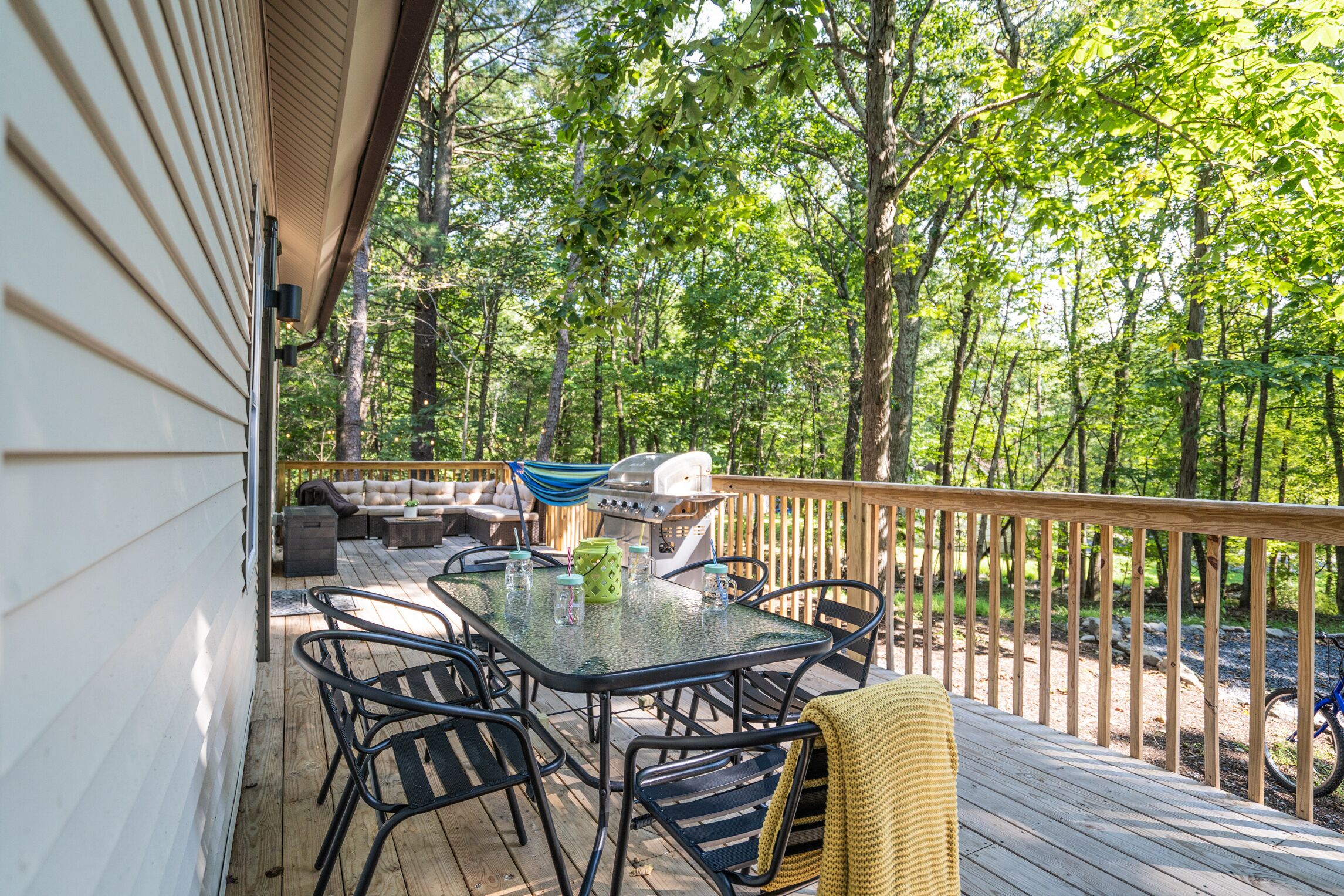 An outdoor deck with a table and chairs, a grill, and a hammock.