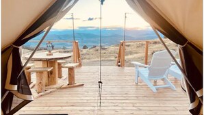A tent with a wooden deck, a round table, and a white chair.