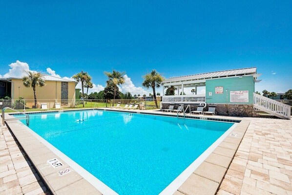 A clear blue pool with lounge chairs and a covered area, surrounded by palm trees and a clear sky. - Fall and Winter 30-40% discounts! Located in the heart of Destin! (Destin)