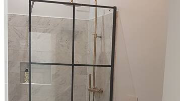 Een moderne badkamer met een douchecabine van glas, een toilet en een douchetoilet.