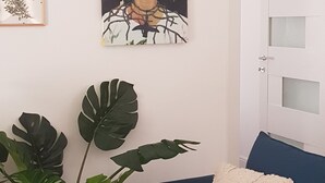 A room with a blue sofa, a white door, and a large plant with broad leaves.