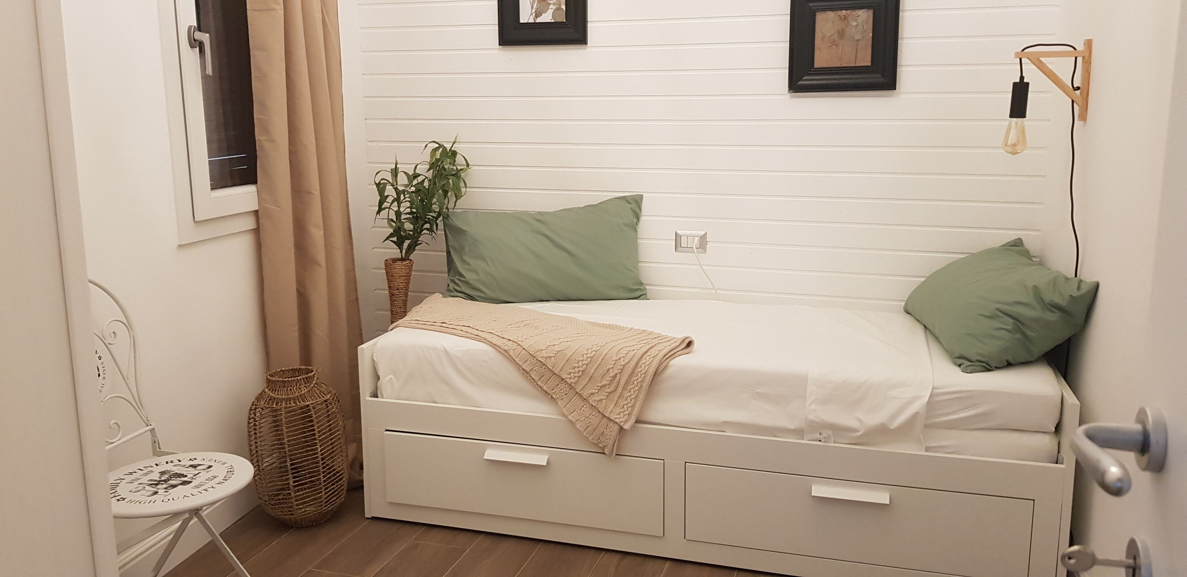 A small, neatly arranged bedroom with a single bed, a small table, and a chair.
