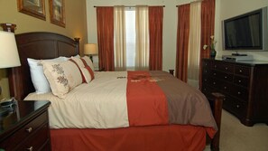 Habitación de hotel con una cama grande, cómoda, televisor y ventana con cortinas.