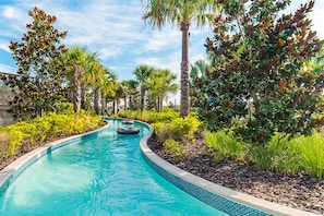 A swimming pool with a curved edge, surrounded by various trees and shrubs. - New Listing! Windsor At Westside Resort, 8mi to Disney & 15mi to Universal - GRH439053 (Kissimmee)
