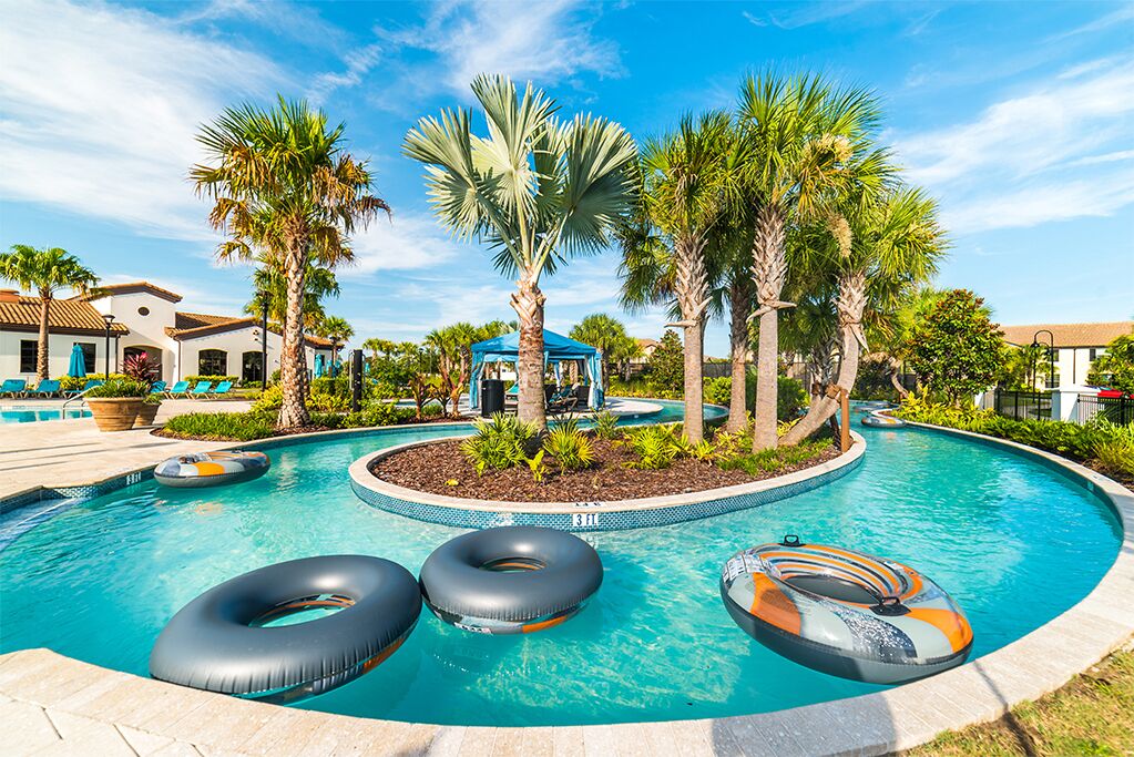 A swimming pool with three inflatable rings, palm trees, and a gazebo.
