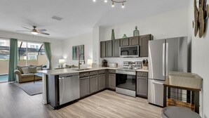 A modern kitchen with grey cabinets, stainless steel appliances, and a central island.