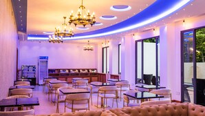A modern dining area with round tables, cushioned chairs, and a central chandelier. - Ari Grand Hotel & Spa (Dhangethi)