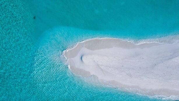 An aerial view of a beach with clear turquoise waters and a sandy area with a distinct shape. - Ari Grand Hotel & Spa (Dhangethi)