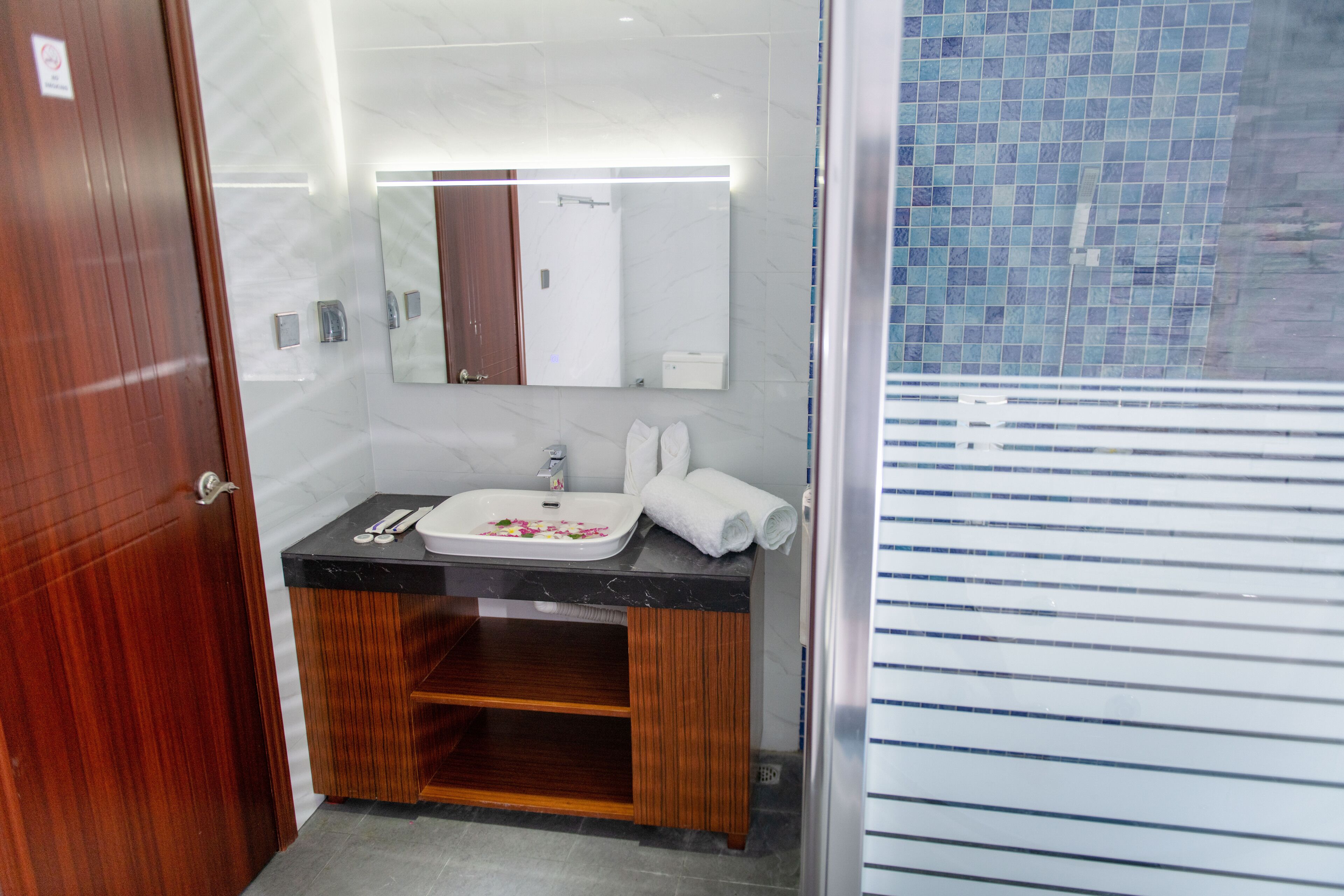 Un baño moderno con tocador de madera, un espejo y cabina de ducha con azulejos.