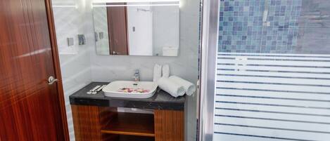 Un baño moderno con tocador de madera, un espejo y cabina de ducha con azulejos.