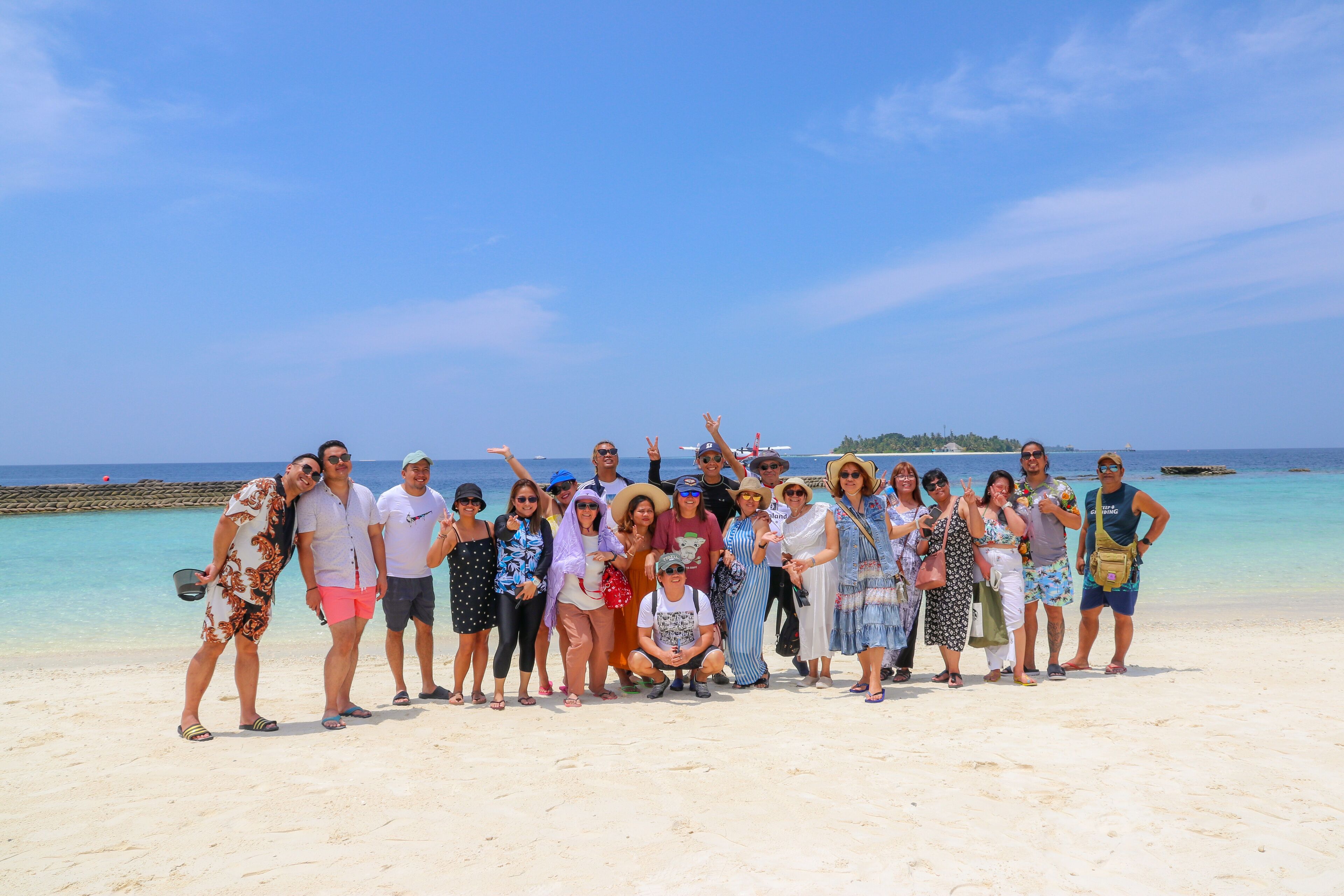 A group of people on a beach with clear skies and calm waters.