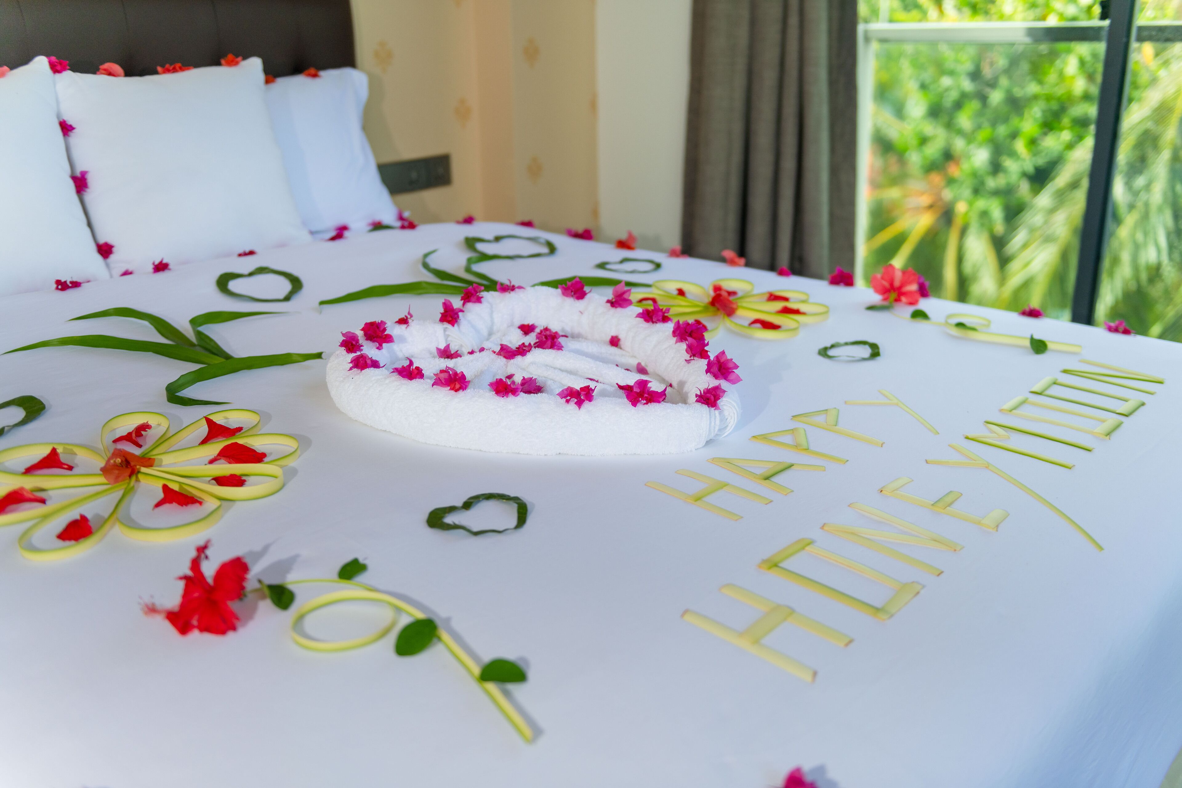 A neatly made bed with a floral arrangement and the words "HAPPY HONEYMOON" on the bedspread.