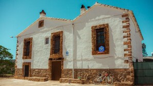 Un edificio de dos plantas con fachada blanca y base de piedra, con una bicicleta estacionada afuera.