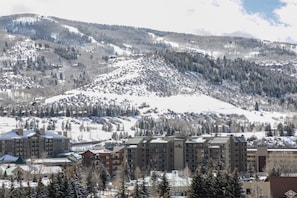 A snow-covered mountain landscape with a residential area featuring multi-story buildings with balconies and a ski slope in the background. - Lodge at 100 W Beaver Creek 607, 3BD Condo in Heart of Avon (Avon)