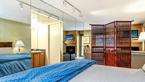 Une chambre d’hôtel avec deux lits, une télévision, un bureau et une armoire.
