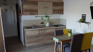 Cozinha compacta com armários de madeira, pia e área de refeições com mesa e cadeiras.