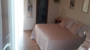 Une chambre à coucher avec un grand lit, une table de chevet, un miroir et une porte donnant sur une autre pièce.