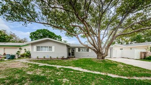 A single-story house with a front yard and a large tree. - Charming Private 1 BR Suite, Pet Friendly & Minutes to Clearwater Beach! (Clearwater)