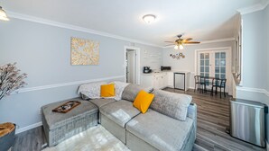A modern living room with a sectional sofa, a dining area, and a kitchen in the background. - Charming Private 1 BR Suite, Pet Friendly & Minutes to Clearwater Beach! (Clearwater)