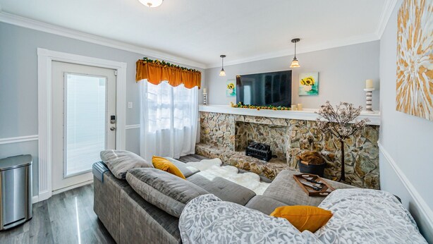 A modern living room with a stone fireplace, a large flat-screen TV, and a cozy seating area with patterned cushions. - Charming Private 1 BR Suite, Pet Friendly & Minutes to Clearwater Beach! (Clearwater)