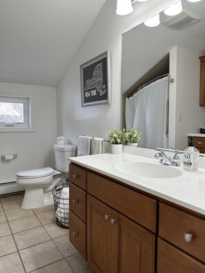 Een bad/douchecombinatie, handdoeken, toiletpapier