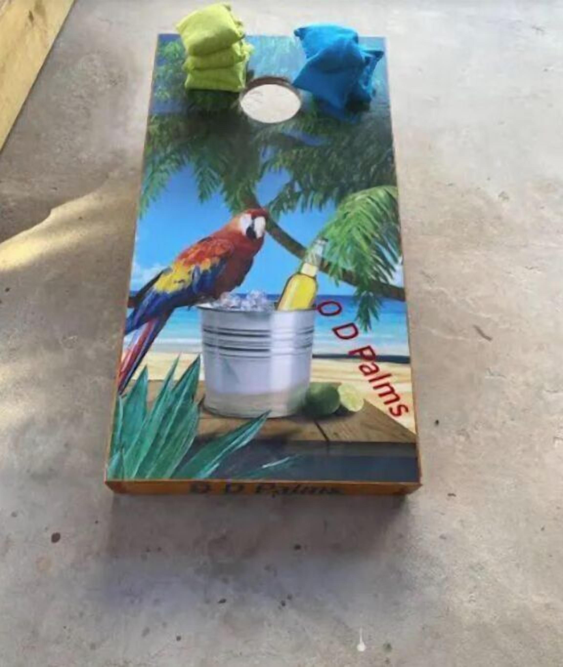 A painted metal surface with a tropical beach scene, including a parrot and a bucket.