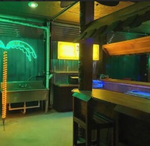 A bar area with a neon light, a pool, and a wooden structure.