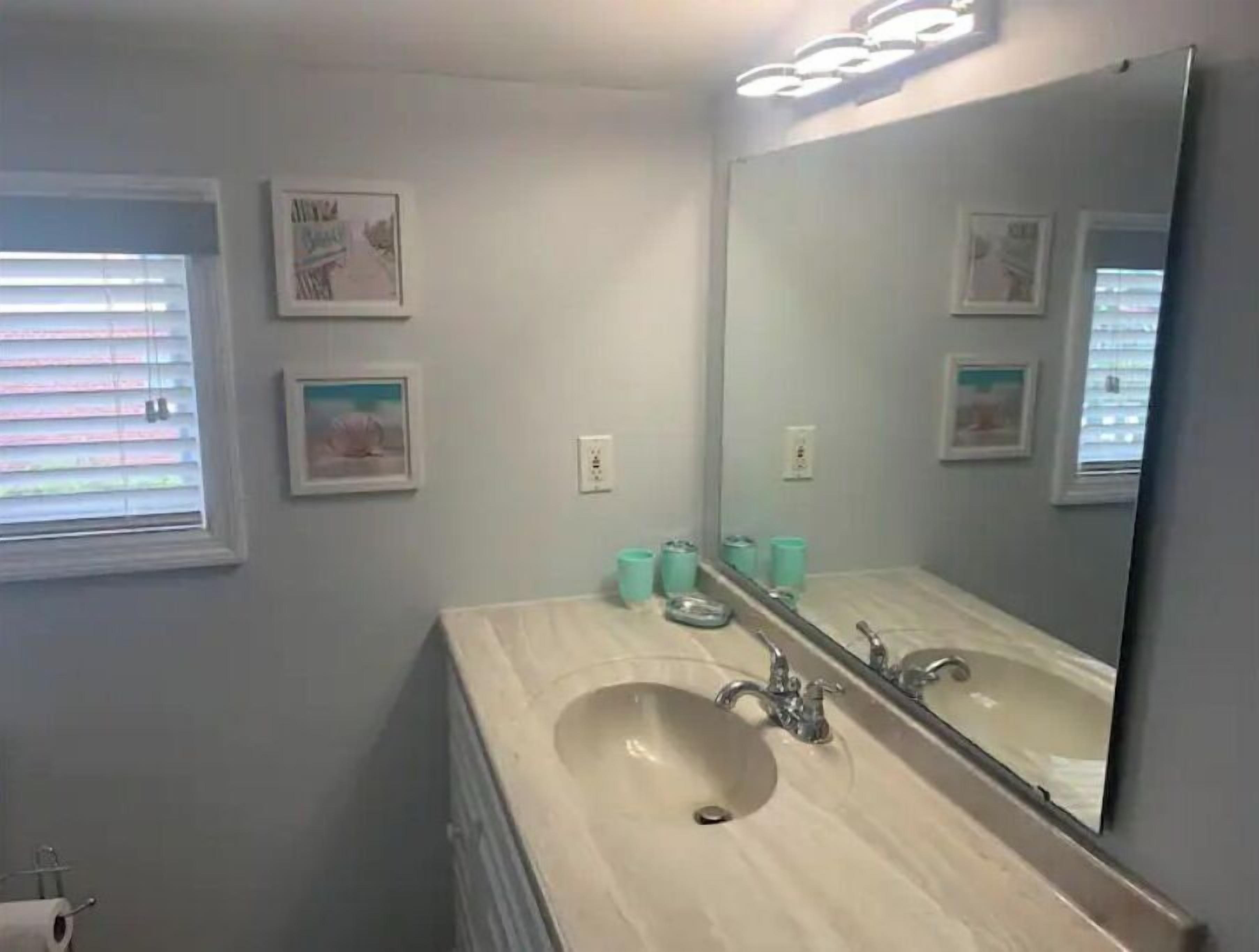 A bathroom with a double sink, a large mirror, and framed pictures on the wall.