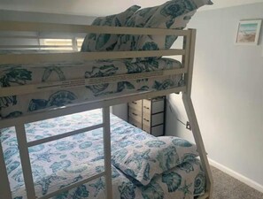 Cozy sleeping quarters feature a bunk bed with a floral-patterned mattress and matching pillows, a cabinet, and a framed picture on the wall.