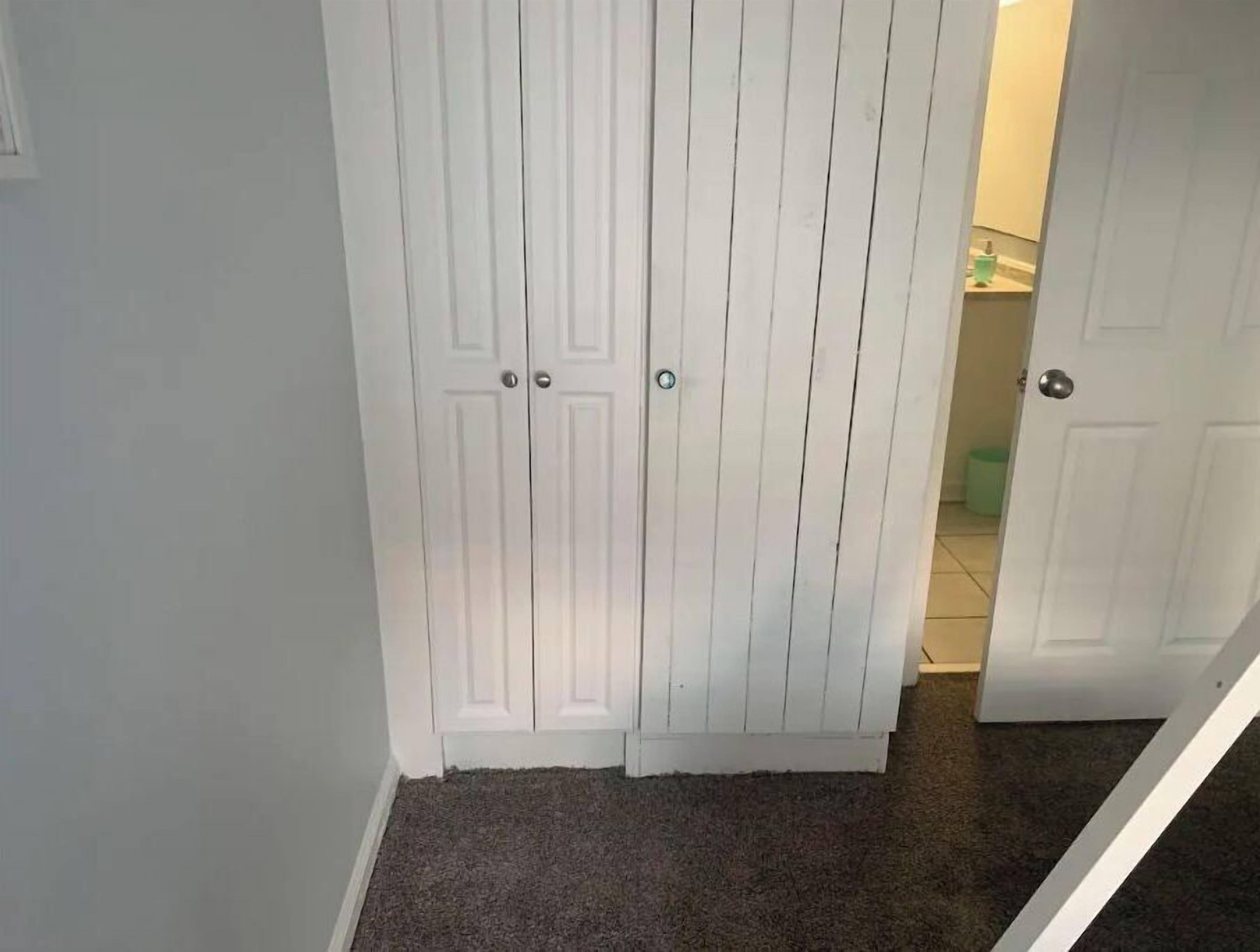 A hallway with a carpeted floor and white double doors.