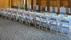 Ein großer Saal mit Holzbalken und hoher Decke, ausgestattet mit Tischen und Stühlen zum Essen.